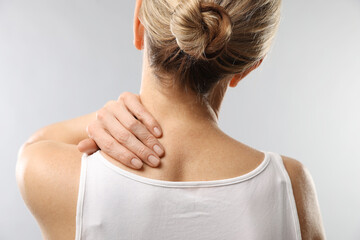 Obraz premium Woman doing neck massage on light grey background, back view