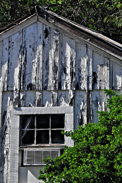 Old derilict house with peeling paint and 1950&rsquo;s era window air conditioning unit