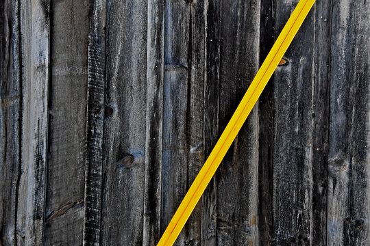 Guy wire guard abstract.  Bright yellow Diagonal guy gard and gray brown old wood slats 