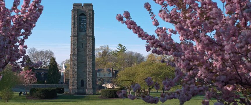 Scenic view of the historic Joseph Dill Baker Carillon in Baker Park, Frederick, Maryland, framed by vibrant pink cherry blossoms on a sunny spring morning.