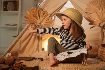 Little girl with drawing of map pointing at something near wigwam indoors © New Africa