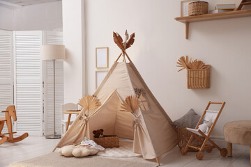 Stylish wigwam with dry leaves in child's room © New Africa