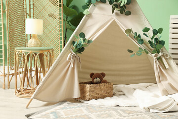 Cute wigwam with leaves and blanket in stylish child's room © New Africa