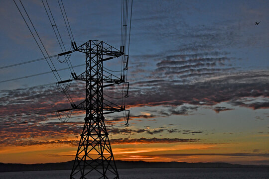Corner high voltage electrical pylon silhouetted against colorful sunset 