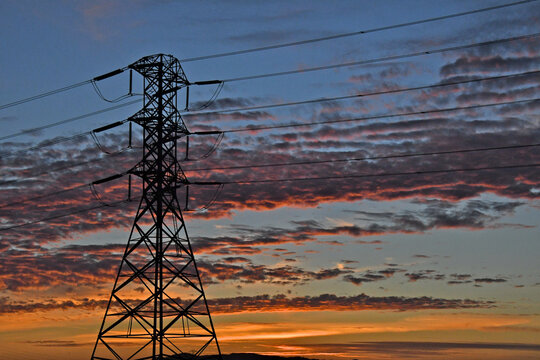 Silhouette of high voltage electrical pylon with colorful clouds at sunset 