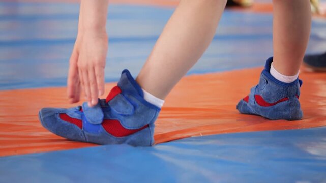 Young athlete adjusting footing. Closeup of athlete preparing for competition. Young competitor adjusting position on padded surface during intense training session