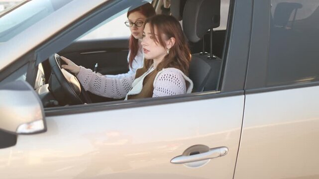 Woman practices driving during lesson while instructor takes notes beside her carefully observing actions and evaluating skills as student focuses on steering and road awareness in training