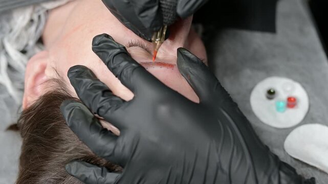 Eyebrow tattoo with color pigment for PMU for real people. A relaxed, mature woman with her eyes closed during the application of permanent makeup to her eyebrow. Permanent eyebrow makeup procedure.