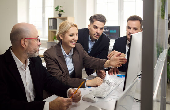 Team business colleagues managers meeting planning. A smiling manager gestures at a computer while teammates review data and discuss ideas in office. Strong teamwork and brainstorming concept.