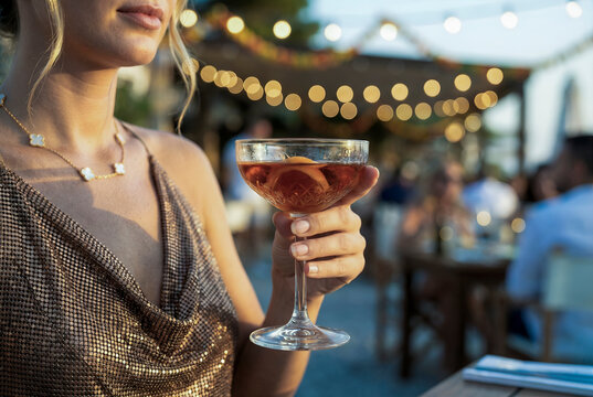 Woman holding cocktail celebrating summer evening party