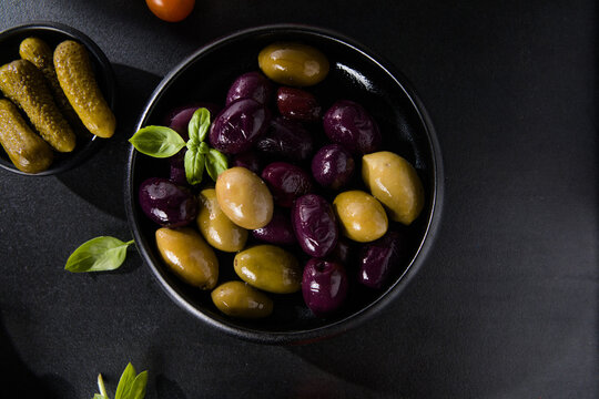 Olives calamata in a ceramic bowl on a black  background.