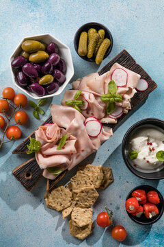 Slices Of Traditional Italian antipasti mortadella Bolognese on a wooden cutting board.