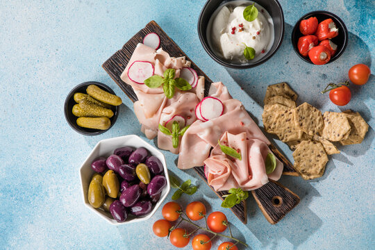 Slices Of Traditional Italian antipasti mortadella Bolognese on a wooden cutting board.