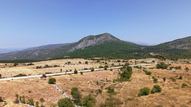 Aerial view of a scenic road winding through the dry fields near Mount Dinara, Croatia