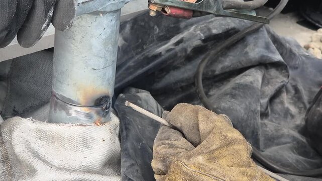 Spot welding a handrail mounting bracket protected by a fireproof welding blanket for safety.