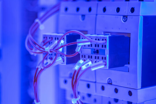 Contactor - electromechanical relay for switching electrical power circuit with blue illumination - close up. Electrical, technology, energy concept