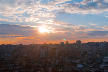 Fototapeta premium Delightful sunset sky with the setting sun and clouds over the city of Istanbul, Turkey in the evening - apartment, residential buildings silhouettes. Cloudscape, cityscape and architecture concept
