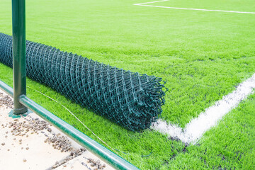 Artificial turf football field under construction with chain link fence rolls, rubber infill surface and fencing installation © AlienCat