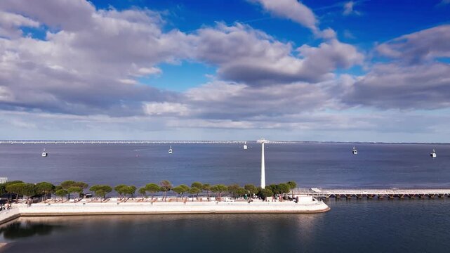 Aerial view of cable cars over Tagus river and waterfront under dramatic clouds. Lisbon, Portugal
