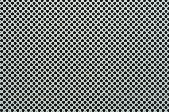A close up shot of a white perforated window film with a dense pattern of small circular holes designed for one way vision.