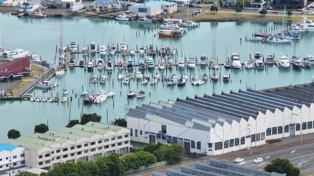 A wide view of a Ahuriri marina filled with sailboats and motorboats docked in the water. The boats are neatly arranged in rows. Napier, Hawkes Bay, New Zealand 