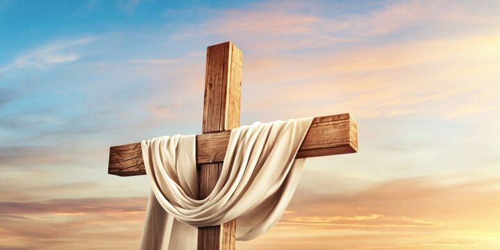 Wooden cross draped with white linen cloth against a dramatic sunset sky