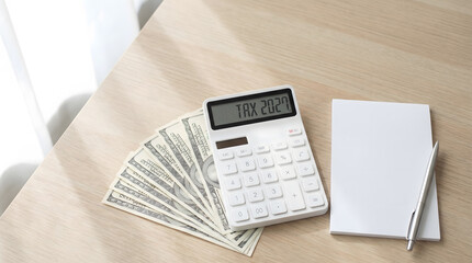Obraz premium White Calculator Tax 2027 Display with Fan of Dollar Bill and Notepad on Desk