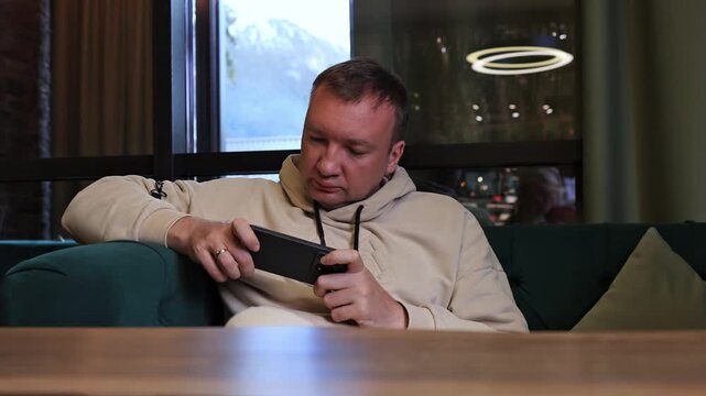 A man plays a game on a smartphone.