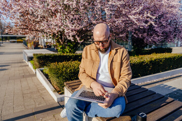 Fototapeta premium White man checking time while working on laptop outdoors spring multitasking