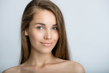Fototapeta premium Portrait of beauty model with make-up, formed eyebrows and long eyelashes. Beautiful young smiling women face with perfect fresh skin. Spa, skincare and wellness. Selective focus. Close-up