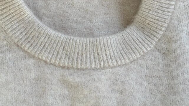 Detailed view of woolen sweater collar emphasizing knit pattern and fabric structure. Suitable for clothing brands, online retail, seasonal fashion campaigns and textile quality presentation.