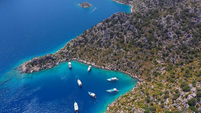 Aerial view of boats anchored in a turquoise cove near Kekova Island with deep blue Mediterranean waters, Antalya, Turkey