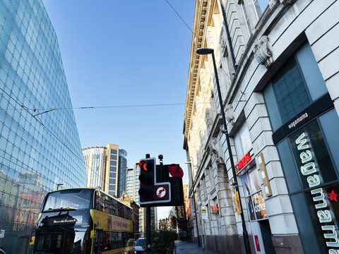 Double decker bus and city street scene with modern glass architecture and Wagamama in Manchester, UK