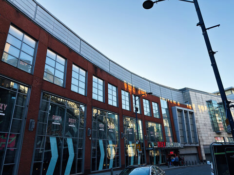 Modern curved brick and glass building with Roxy Ballroom venue on a busy street in Manchester UK