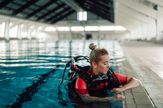 Woman in scuba gear learning diving skills during training in an indoor swimming pool, focusing on progress