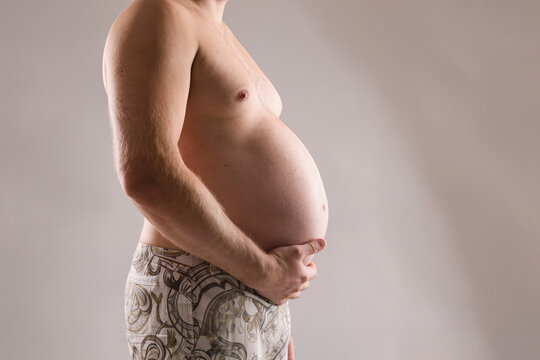Overweight man holding large belly, obesity and weight gain concept, unhealthy lifestyle health risk