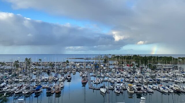 Beautiful 4K time-lapse overlooking Ala Wai Yacht Harbor in Honolulu, Hawaii. Hundreds of sailboats and yachts fill the marina beneath dramatic tropical clouds, creating a scenic waterfront view near 