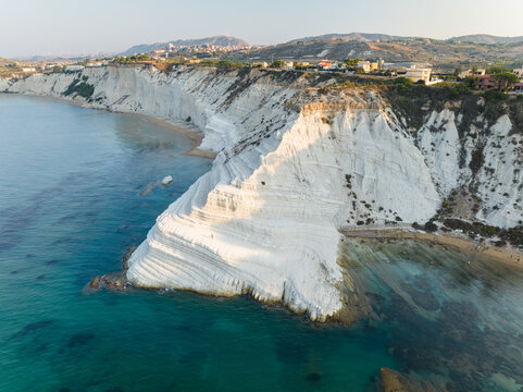Aerial view of the white marl cliffs of the Stair of the Turks overlooking the turquoise Mediterranean sea and rugged coastline in Realmonte, Sicily, Italy.