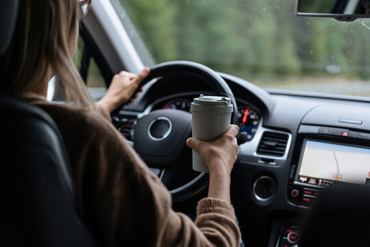 Woman driving car with coffee