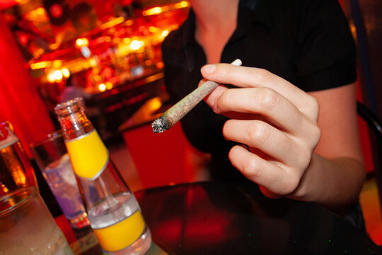 A woman holds a marijuana cigarette