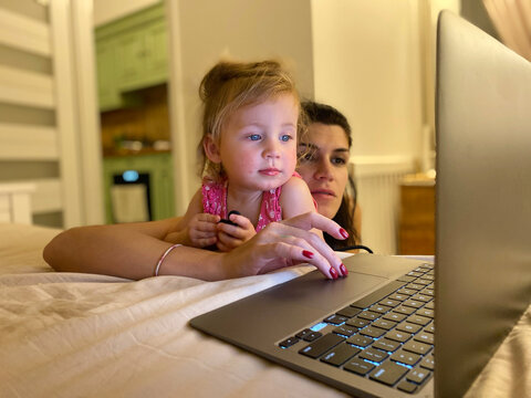 Mother trying to work on laptop around her baby