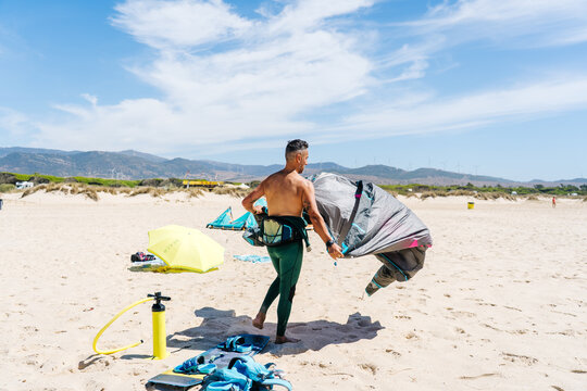 Kite surfer preparing equipment on sandy beach