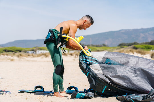Person inflating kite for kitesurfing on beach