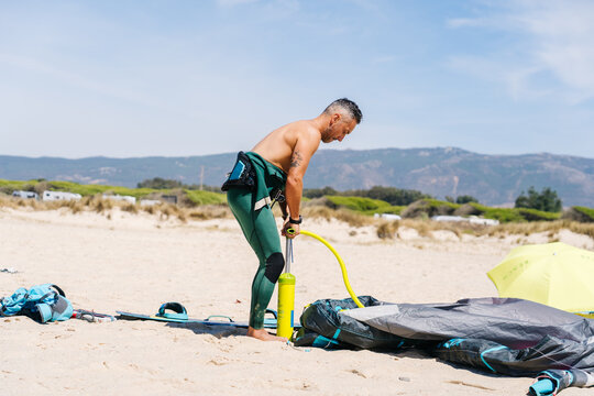 Person inflating kite before kitesurfing on beach