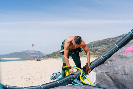 Person inflating kite before kitesurfing on sandy beach