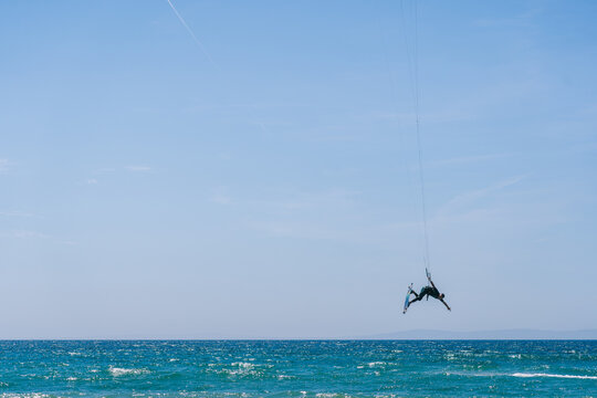 Kitesurfer performing an acrobatic jump on an ocean wave