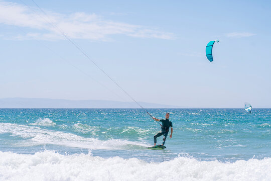 Kitesurfer riding ocean waves on a summer day