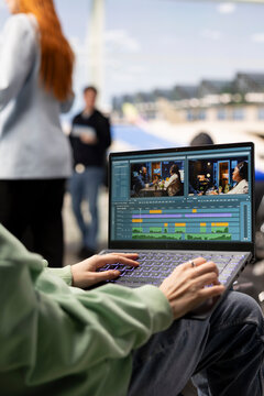 Young woman videographer working on video production in airport waiting area, editing footage and adding transitions for a cinematic film project. Location independent career and flexibility.