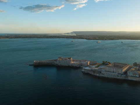 Aerial view of the historic Castello Maniace fortress on the tip of Ortygia island surrounded by the blue Mediterranean sea in Syracuse, Sicily, Italy.