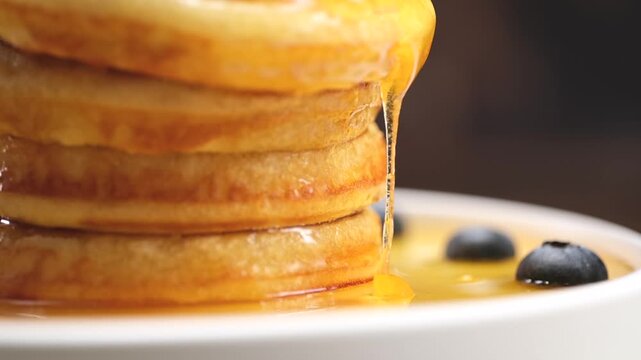 Pancakes stack with dripping honey syrup and blueberries